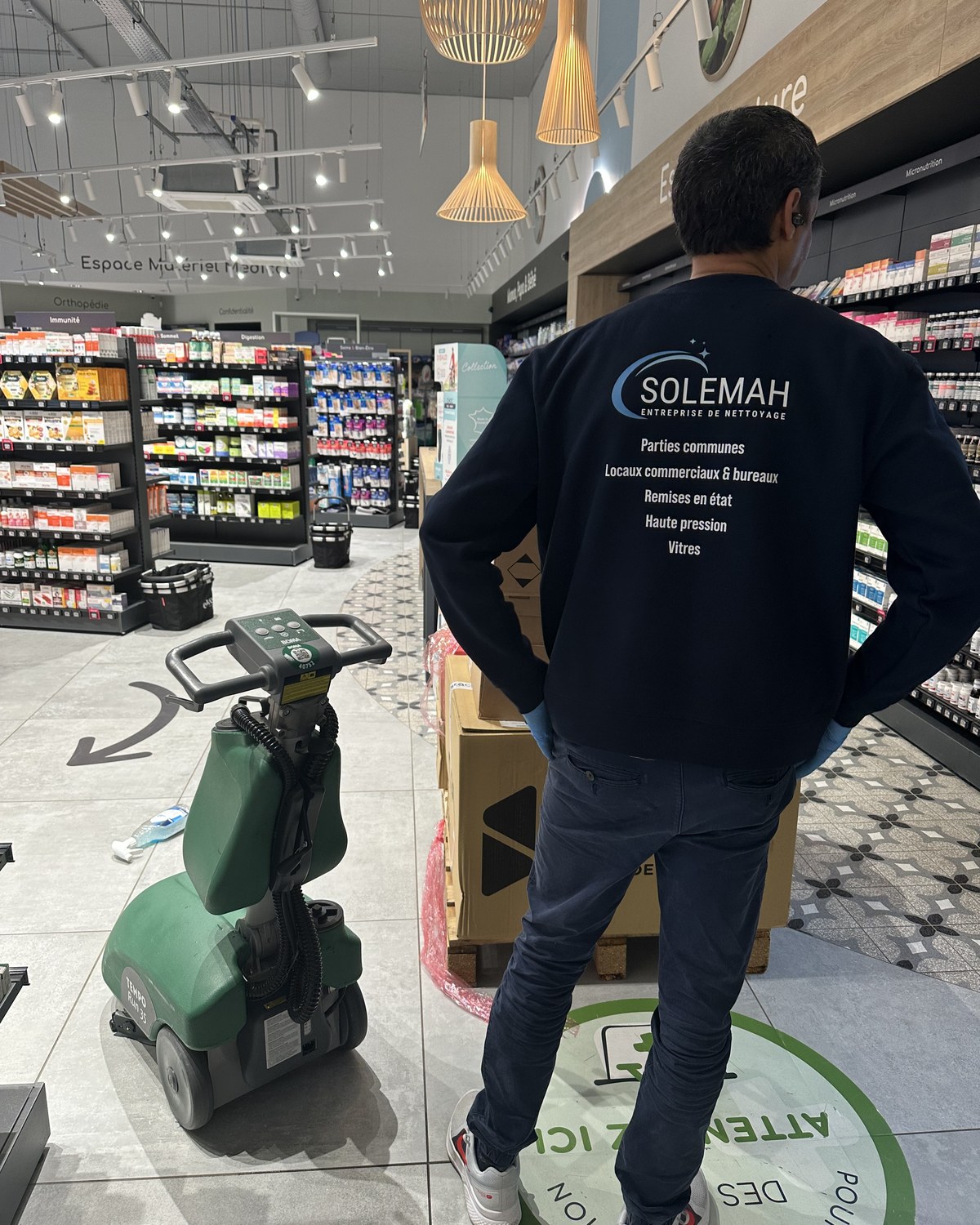 Salarié SOLEMAH de dos avec autolaveuse dans un commerce